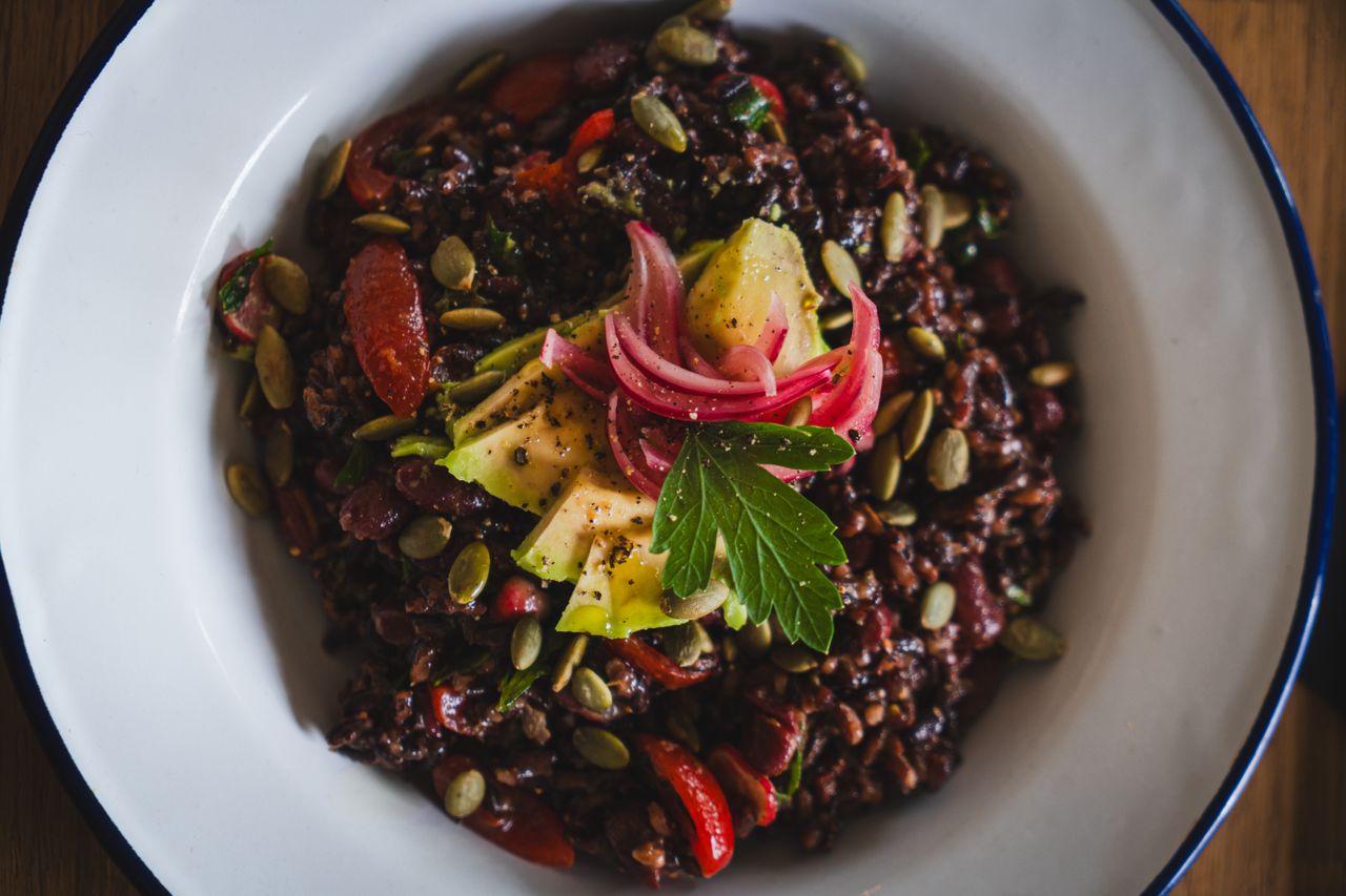 why-choose-us Healthy vegan black rice salad topped with avocado, pickled onions, and pumpkin seeds.